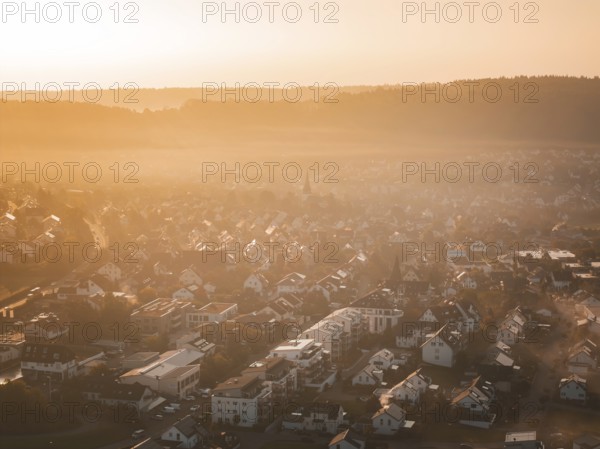 Aerial view of a village in morning fog at sunrise with warm orange light, Calw Stammheim, Black