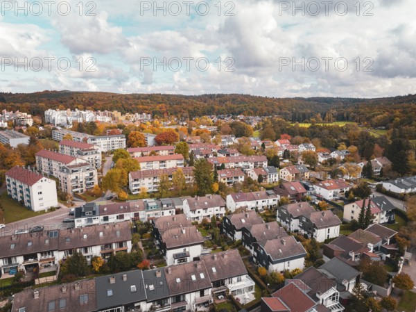 Residential area with terraced houses and surrounding colorful autumn trees in slightly cloudy
