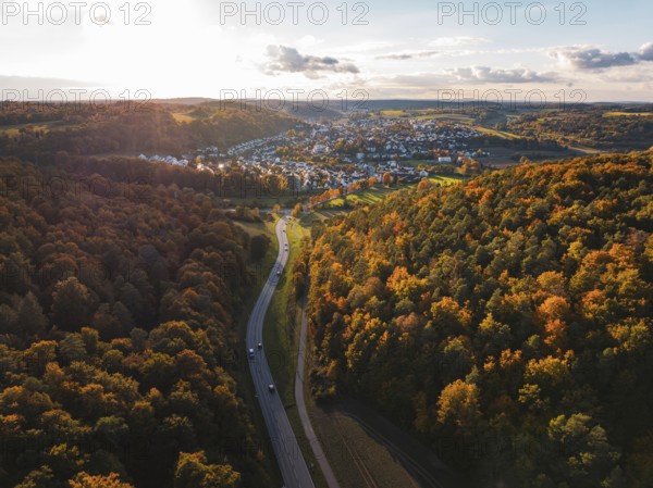 Autumn forest landscape with a road leading to a small settlement, Aidlingen, Böblingen district,