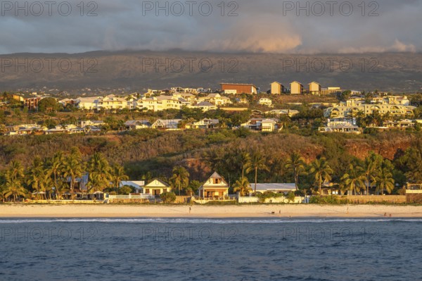 The bright sandy beach of the Saint-Gilles lagoon with bathers merges into a coastal landscape with