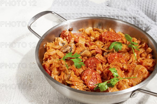 Polish dish bigos, in a stainless steel pan, stewed meat with cabbage, chorizo sausages, mushrooms,