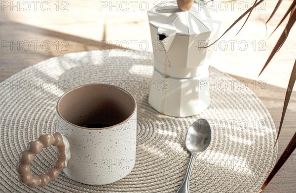 Making morning coffee, geyser coffee maker and mug, in bed colors, on a wooden table, natural