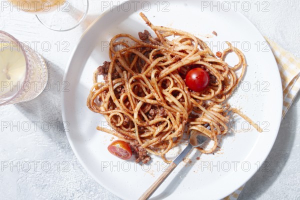 A plate holds freshly cooked spaghetti topped with flavorful meat sauce and garnished with bright