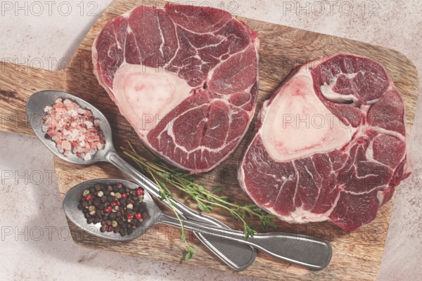 Knuckle on the bone, raw ossobuco meat, on a wooden chopping board, with spices, top view, no