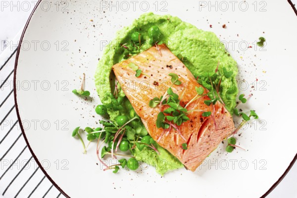 Delicious grilled salmon is placed elegantly on creamy green pea puree. Fresh microgreens and peas