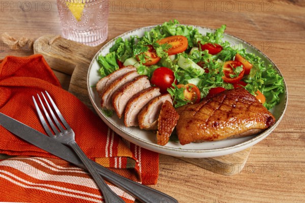 Delicious grilled duck breast served with fresh garden salad and cherry tomatoes at a rustic dining