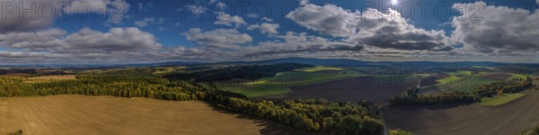 A breathtaking landscape with vast fields and deep blue skies. Sunlight shines onto the green area.