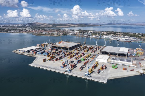 A busy port with shipping containers and cranes. Aerial view to new container unloading terminal of