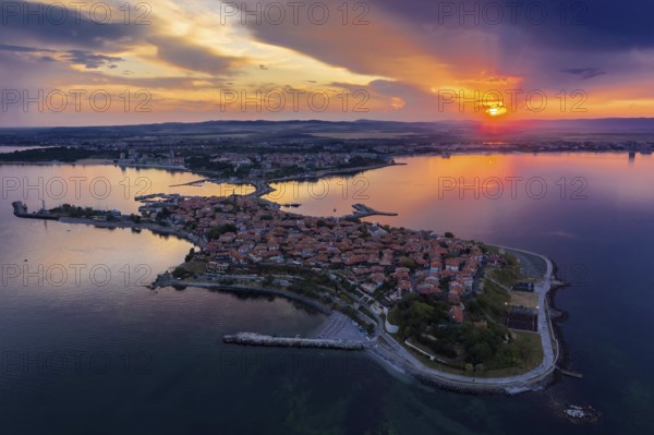 Aerial view of a peninsula at sunset with an orange sky and calm sea. Aerial view to old town of