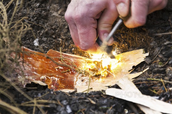 Male hand starts fire with magnesium fire steel, fire striker Prague Czech republic