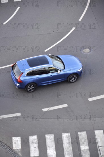 Blue unrecognizable car moving on road with broken line near pedestrian crossing, driverless