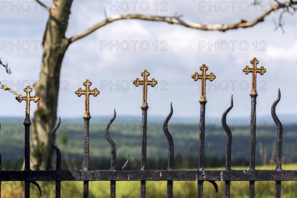Beautiful small iron crossed fence decoration, graveyard wall with green woods in background, life