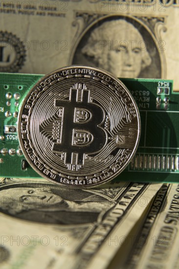 Silver bitcoin coin with dollars and computer motherboard, cryptocurrency mining and investing