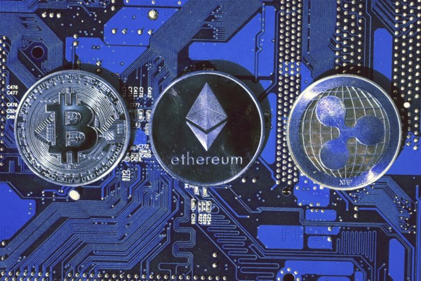 Bitcoin, Ethereum, Ripple coins on computer motherboard, cryptocurrency investing concept Prague,