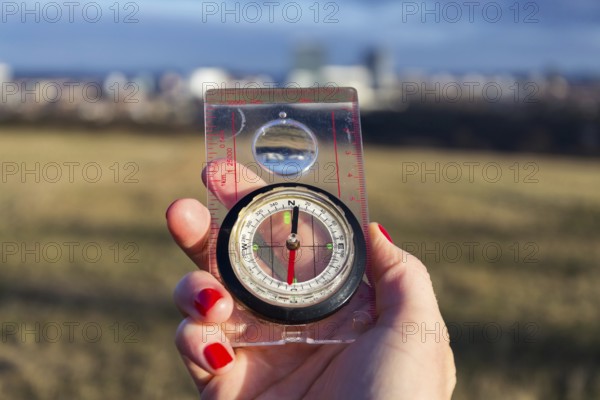 Female hand holding glass compass, nature in background, sunny autumn day, life change and new