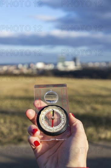Female hand holding glass compass, nature in background, sunny autumn day, life change and new