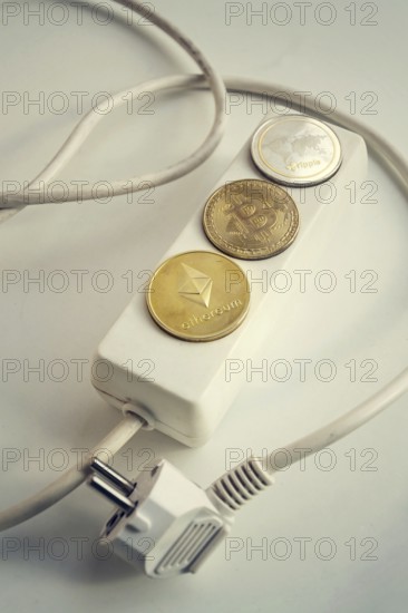 Bitcoin, Ethereum and Ripple coins lying on power strip extension cord with 3 sockets, largest