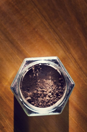 Cocoa powder in glass jar lying on wooden brown table, flat lay view, healthy diet Prague Czech