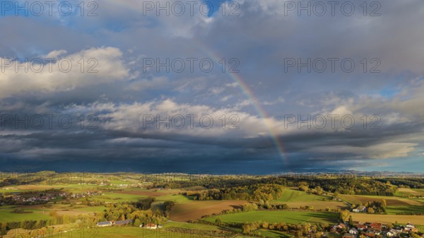 A rainbow stretches across the vast fields and villages. The scene shows vivid colors under a