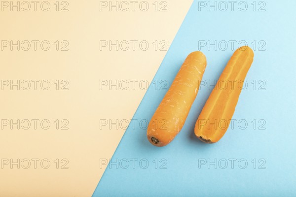 Orange Carrot on orange and blue pastel paper background. Side view, copy space, flat lay. healthy