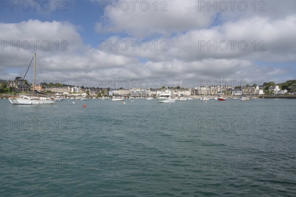 A series of small sailboats, probably optimists, with red and white ringed sails, move in formation