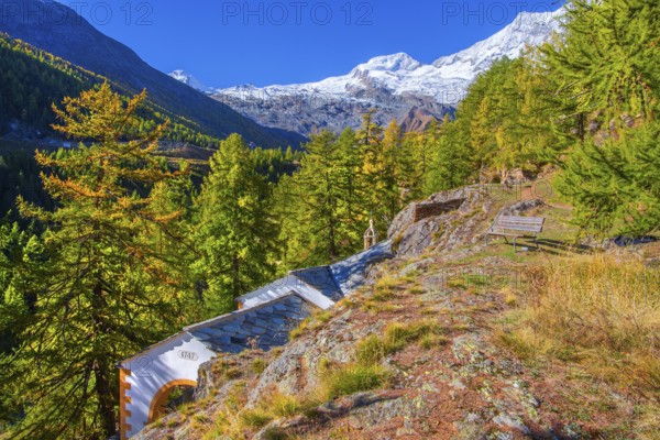 Chapel zur Hohe Stiege on the historic Kapellenweg with Allalin 4027m and Alphubel 4206m in autumn,