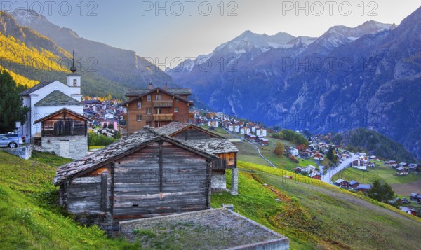 City overview on a mountain terrace above the valley with Ulrichshorn 3925 m after sunset, Grächen,