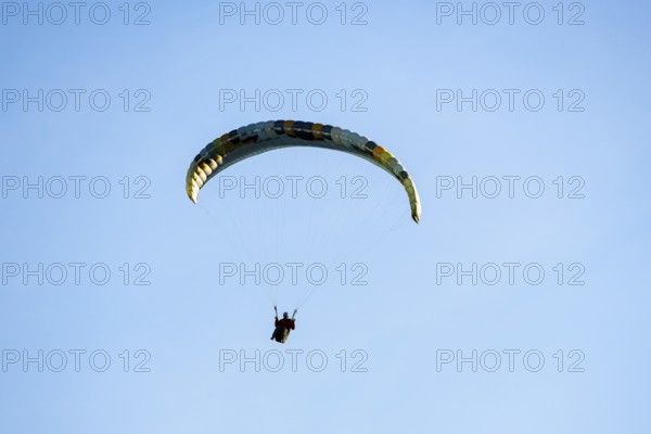 A single paraglider in front of a simple and minimalistic blue sky, Schwangau, Ostallgäu, Swabia,