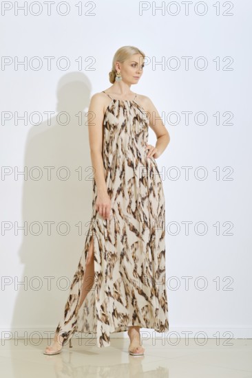A woman stands confidently wearing a fashionable long dress featuring a unique pattern. She poses