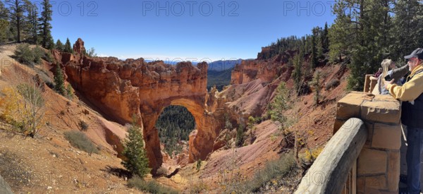 Visitors look at a majestic rock arch from a vantage point in the canyon, Bryce Canyon National