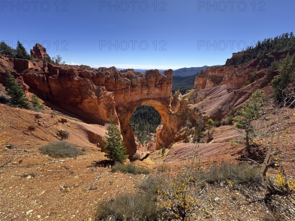 Expansive view of a rocky arch surrounded by clear, deep blue sky, Bryce Canyon National Park is