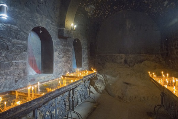The room with candlelight creates a quiet, subdued atmosphere with stone walls, Khor Virap