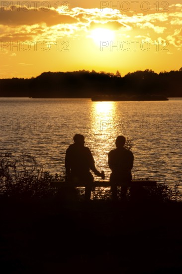 Two men sitting on a bench at sunset at Lake Gudelack, Lindow (Mark), Stechlin-Ruppiner Land nature