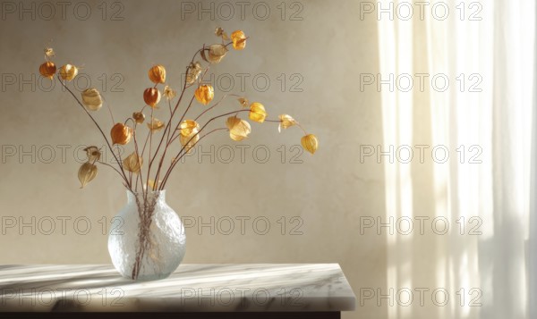 A vase of dried flowers sits on a table in a room with a window. The flowers are yellow and brown,