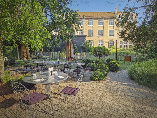 Rustic outdoor restaurant terrace with a classic, european garden aesthetic. The seating area