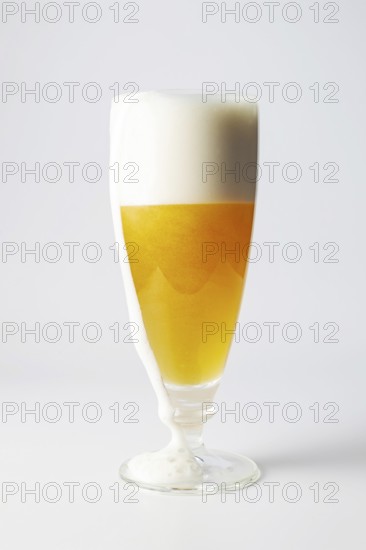 A glass of beer with foam running off, copy space