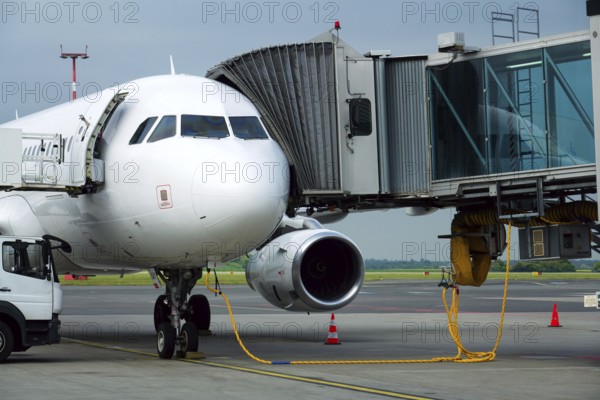 Charter airline airplane preparing for flight on airport runway with connected jet boarding bridge
