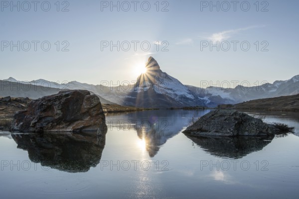 Matterhorn Mountain and Reflection in Lake Stellisee at Sunset. Sun is Setting behind the Mountain.