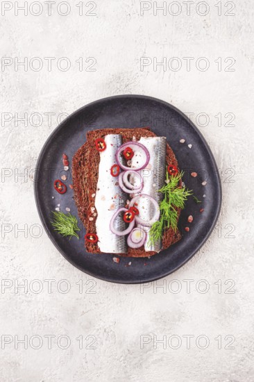 Sandwiches, herring fish, on dark rye bread, sprinkled with onion, chili pepper and herbs, on a