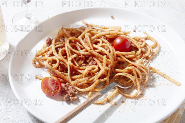 A plate holds freshly cooked spaghetti topped with flavorful meat sauce and garnished with bright