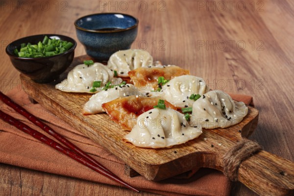 Gyoza Japanese dumplings, fried, with sauce, with green onion and sesame seeds, no people,