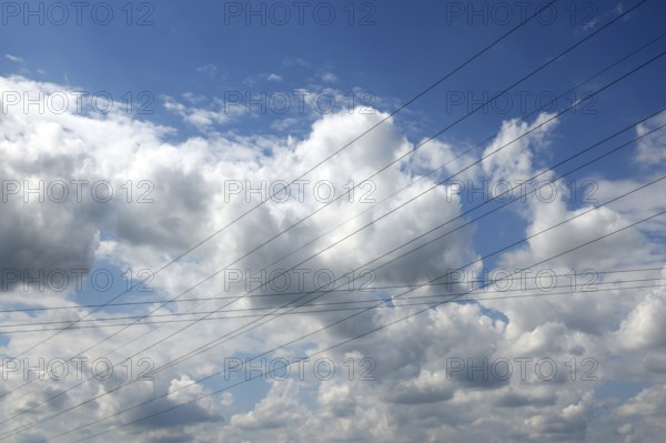 Intersecting high-voltage lines cut through a blue sky with white clouds, Upper Bavaria, Bavaria,