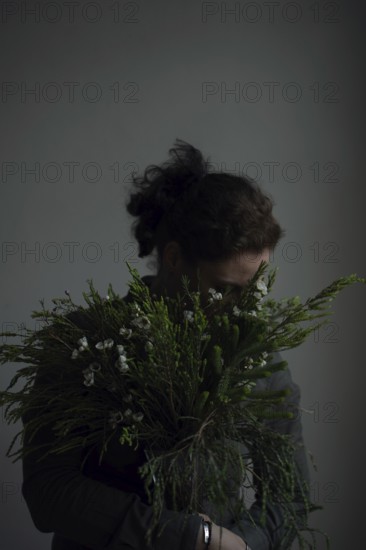 Woman holding ostrich with grasses, face covered