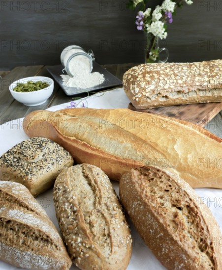 Various freshly baked artisanal breads and rolls presented on a white cloth on a rustic wooden
