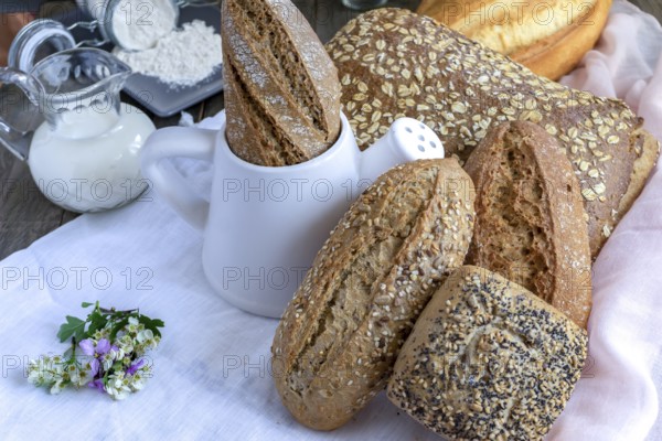 Freshly baked artisanal bread assortment, including baguettes, rolls, and loaves, with flour and
