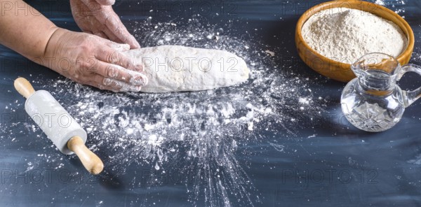 Female hands preparing fresh artisanal bread dough on a dark kitchen table. Baking ingredients