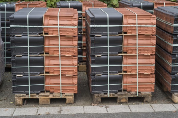 Borken, NRW, Germany, New terracotta and black roof tiles packaged on wooden pallets for