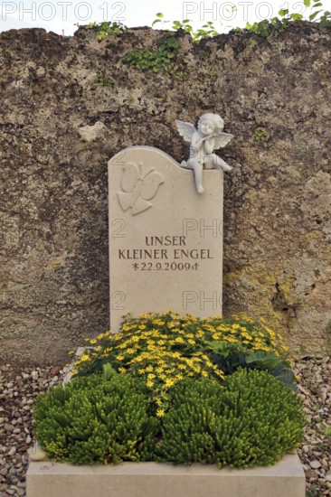 Children's grave with angel figure and beautiful floral decoration on a cemetery wall, Upper