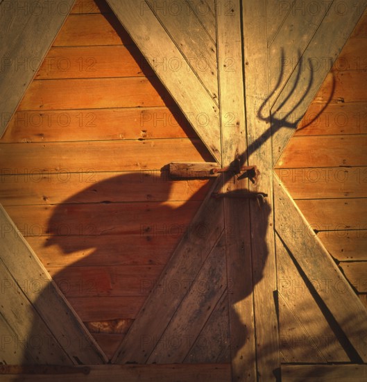 Farmer with a pitchfork against a barn door in Vermont, USA