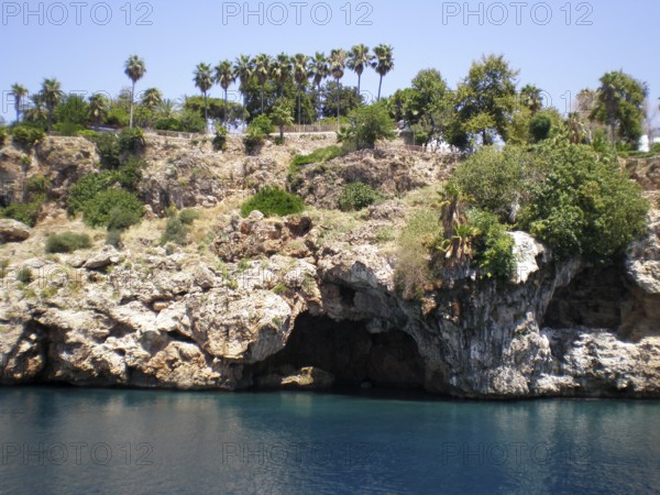A panoramic view of a grotto with caves in the mountain cliffs jutting out from the azure and